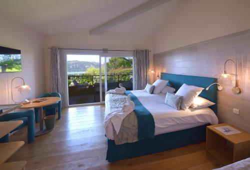 a bedroom with a bed and a table and a balcony at Hôtel Alivi Di Santa Giulia in Porto-Vecchio