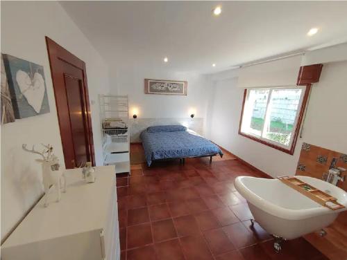 a bathroom with a tub and a sink and a bed at Hospedaje Athena in Pontevedra