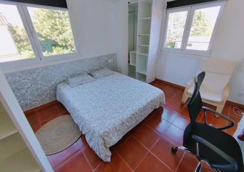 a bedroom with a bed and two chairs and two windows at Hospedaje Athena in Pontevedra