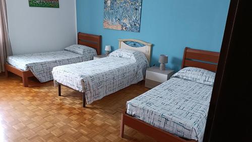 3 Betten in einem Zimmer mit blauen Wänden in der Unterkunft La Casa delle Magnolie in San Canzian dʼlsonzo