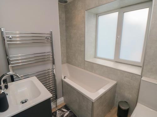 a bathroom with a sink and a tub and a window at 1 Staveley Cottages in Weaverthorpe