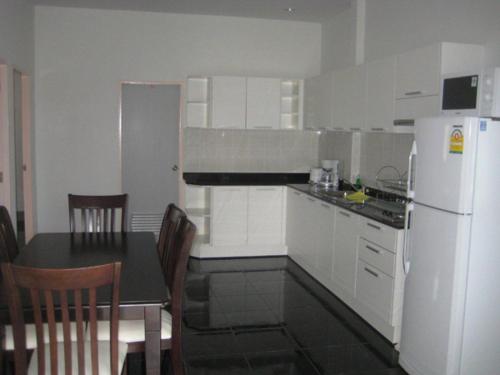 a kitchen with a table and a white refrigerator at Baan Finland - 2 Bedroom apartment in Hua Hin
