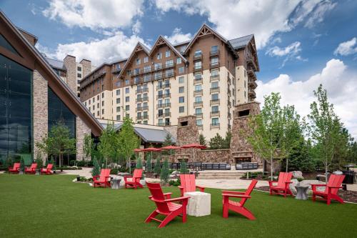 オーロラにあるGaylord Rockies Resort & Convention Centerの芝生の上に赤い椅子とテーブルが並ぶ大きな建物