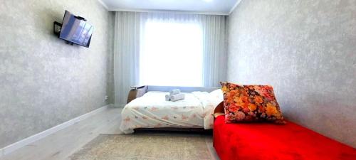 um quarto com uma cama e um sofá vermelho em Аэропорт 10 минут жк Будапешт163 em Astana