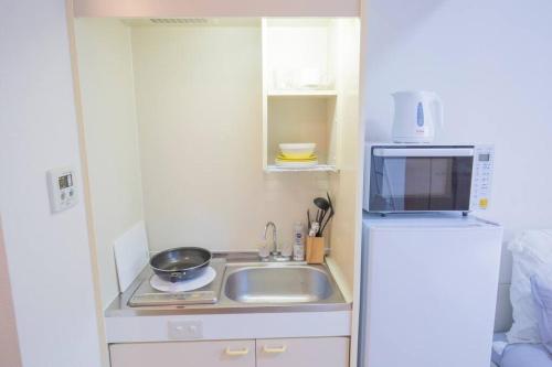 a small kitchen with a sink and a refrigerator at 閑静な住宅街_暖かく居心地の良いデザイン YoW-4 in Tokyo