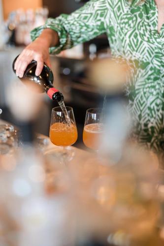 a person pouring wine into two wine glasses at Boutique Hotel Eschenlohe in Schenna