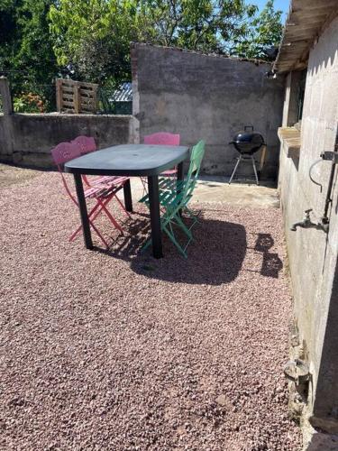 a table and three chairs sitting next to a grill at Chez Mélanie in Neuilly-le-Réal