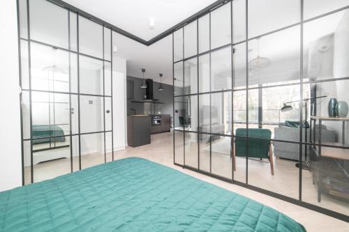 a bedroom with a green bed and large windows at VacationClub – Ogrody Pieniawskie Apartament 21 in Polanica-Zdrój