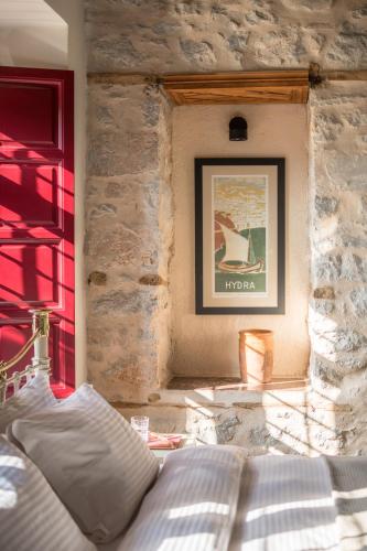 a bedroom with a bed in a stone wall at FOS Hydra residence in Hydra
