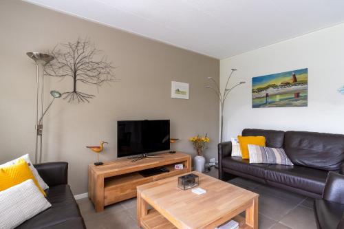 un soggiorno con divano e TV di Landhuis Tempelierweg 23 a Den Burg