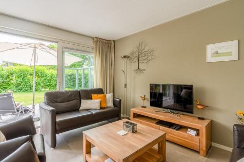 Una sala de estar con un sofá y un televisor. en Landhuis Tempelierweg 23, en Den Burg