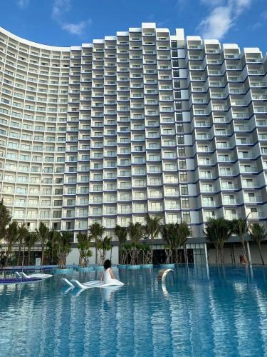 a woman in a pool in front of a large building at The Cam Ranh Resort all Luxury Service in Miếu Ông