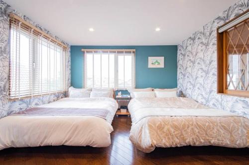 three beds in a room with blue walls and windows at THE BLAUBAUM TOYA in Lake Toya