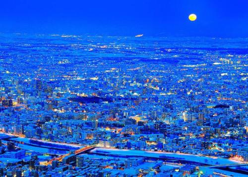 a view of a city at night with the moon at MS STUDIO in Asahikawa