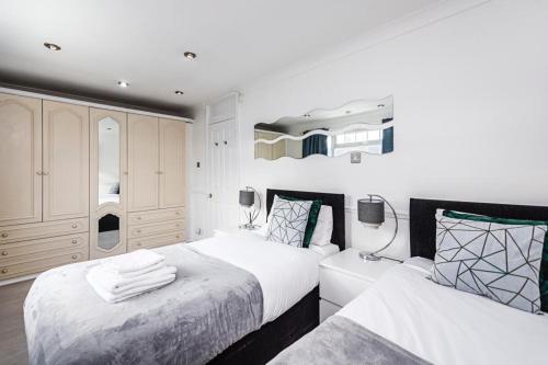 2 bedden in een slaapkamer met witte muren bij Elite 2 Bedroom House in Chadwell Heath/ Romford with Free Wifi and Parking upto 4 guests in Goodmayes
