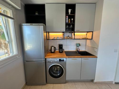 een keuken met een wasmachine en een wastafel bij Superbe appartement ensoleillé - Vue mer, Clim et Parking in Villeneuve-Loubet