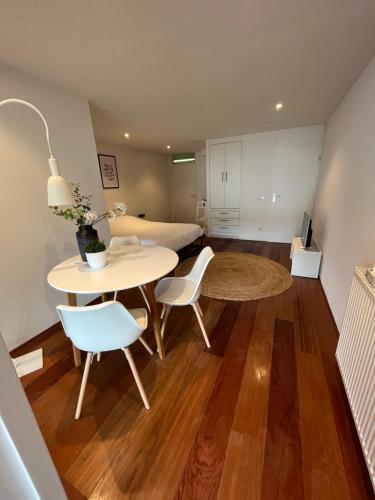 een woonkamer met een tafel, stoelen en een bed bij Studio J. in Egmond aan Zee