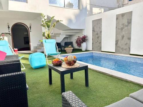 - un salon avec une table et une piscine dans l'établissement Villa du Bey à La Marsa, à La Marsa