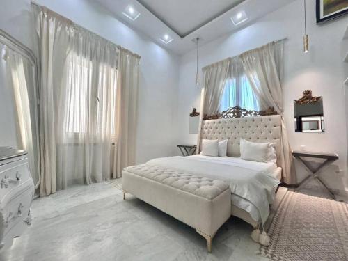 a white bedroom with a large bed and a window at Villa du Bey à La Marsa in La Marsa
