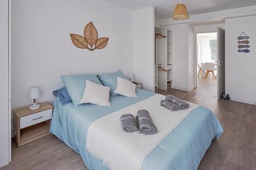 a bedroom with a blue bed with slippers on it at Logement récent 3 chambres à 200m mer et commerces in La Bernerie-en-Retz