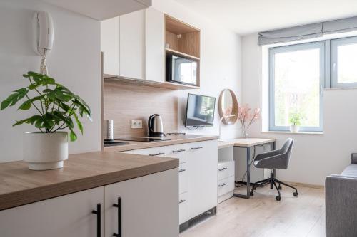une cuisine avec des placards blancs et un bureau avec une plante en pot dans l'établissement RentPlanet - Studio Dyrekcyjna, à Wrocław