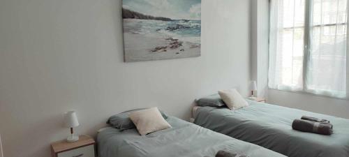 two beds in a room with a picture on the wall at Logement récent 3 chambres à 200m mer et commerces in La Bernerie-en-Retz