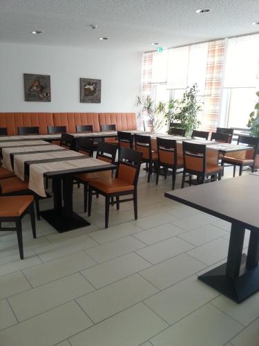 a dining room with tables and chairs and windows at Hotel Quellenhof in Salzgitter