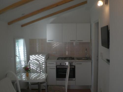 a kitchen with white cabinets and a stove and a table at Apartments Zora in Pirovac