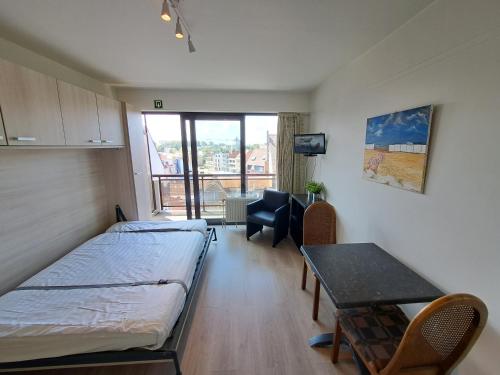 a room with a bed and a table and a desk at THOGE Koksijde in Koksijde