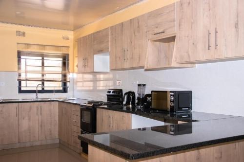 a kitchen with wooden cabinets and a black counter top at JRK Apartments & Services Limited in Lusaka