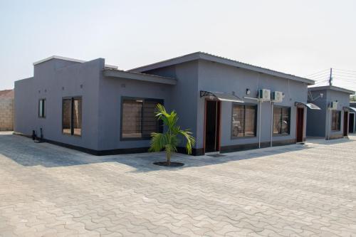 a house with a palm tree in front of it at JRK Apartments & Services Limited in Lusaka