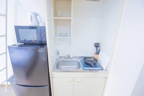 a small kitchen with a sink and a microwave at 閑静な住宅街_暖かく居心地の良いデザイン EoS-J in Tokyo