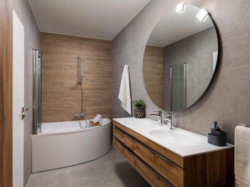 uma casa de banho com uma banheira, um lavatório e um espelho. em Magnificent Luxury Villa Dominic em Privlaka