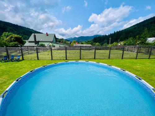 ein großer blauer Pool auf einem Feld neben einem Zaun in der Unterkunft Svitlana in Tatariw