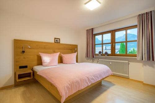 Schlafzimmer mit einem Bett mit rosa Kissen und einem Fenster in der Unterkunft Ferienwohnung Alpentraum-Panorama Chalet in Oberstdorf