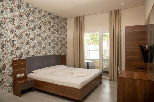 a bedroom with a bed and a tv and a window at Hotel Dyrrah in Durrës