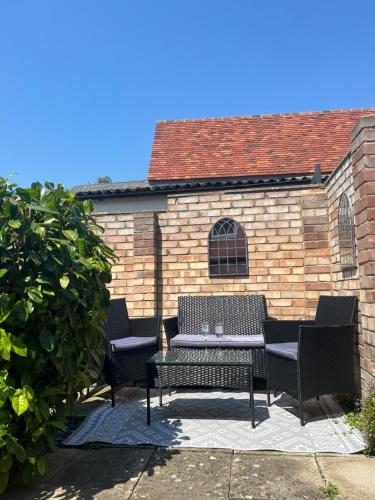 a patio with a table and chairs in front of a brick wall at Almond Cottage Clare - 2 bedroom English Cottage in Clare