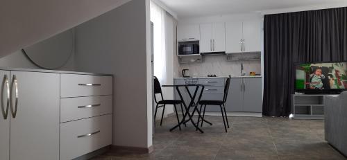 a kitchen with white cabinets and a table with chairs at Guesthouse Next to beach in Batumi