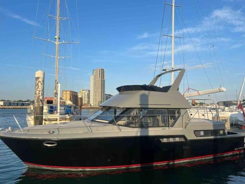 a black and white boat sitting in the water at YACHT "X" - 44 FOOT MODERN YACHT ON 5 STAR OCEAN VILLAGE MARINA - minutes away from city centre and cruise terminals, Free parking ,SPA package available! in Southampton