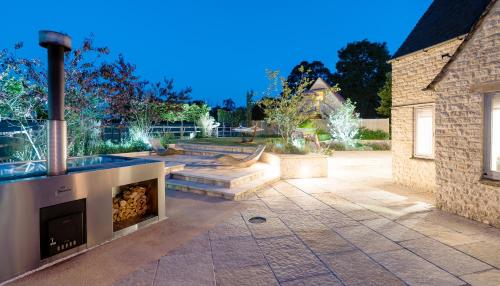 a patio with a fireplace in a yard at Warren House and Spa boutique Cotswold stay in Cirencester