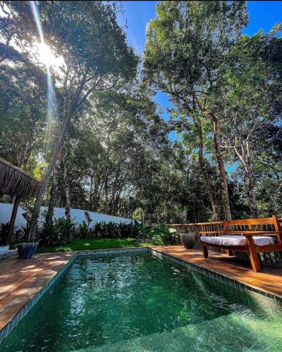 a pool with a bench next to a wooden deck at Villa Sagui Trancoso in Trancoso