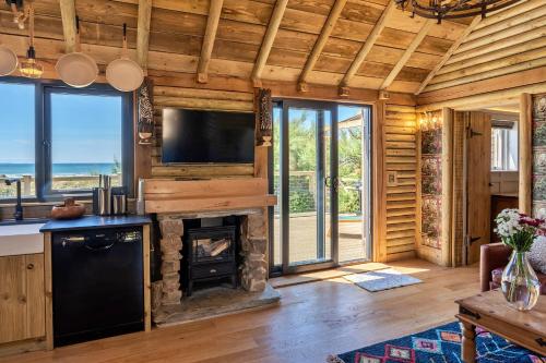 a living room with a fireplace and a tv at Finest Retreats - Driftwood in Poundstock