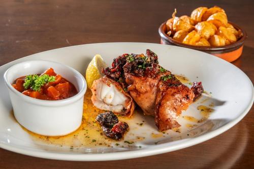 a plate of food with chicken and vegetables and a bowl of chips at Hotel Rex in Weymouth