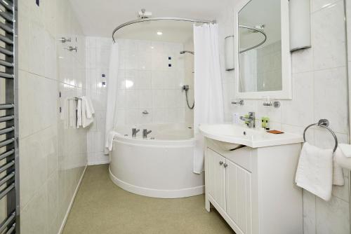 a white bathroom with a tub and a sink at Hotel Rex in Weymouth