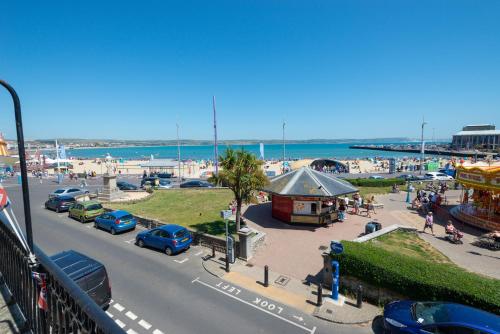 a view of a beach with cars parked in a parking lot at Hotel Rex in Weymouth