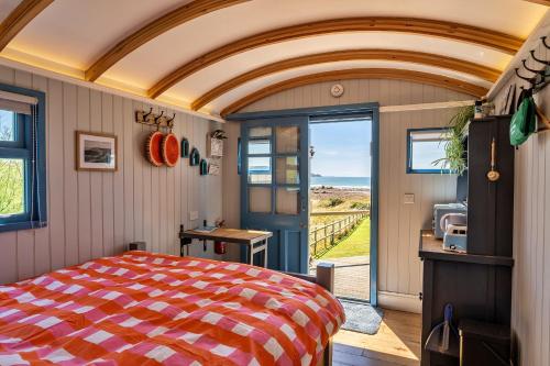 1 dormitorio con cama y vistas al océano en Finest Retreats - Driftwood, en Poundstock