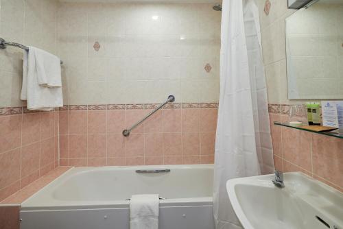 a bathroom with a tub and a sink and a bath tub at Hotel Rex in Weymouth