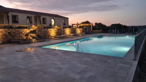 a swimming pool in front of a house with a stone wall at Tenuta Paltusa in Calangianus