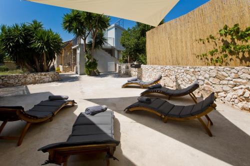 a group of chairs and tables in front of a stone wall at Robinson house T'n'T in Hvar