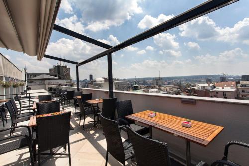 a balcony with tables and chairs and a view of the city at Prince Rooftop in Belgrade